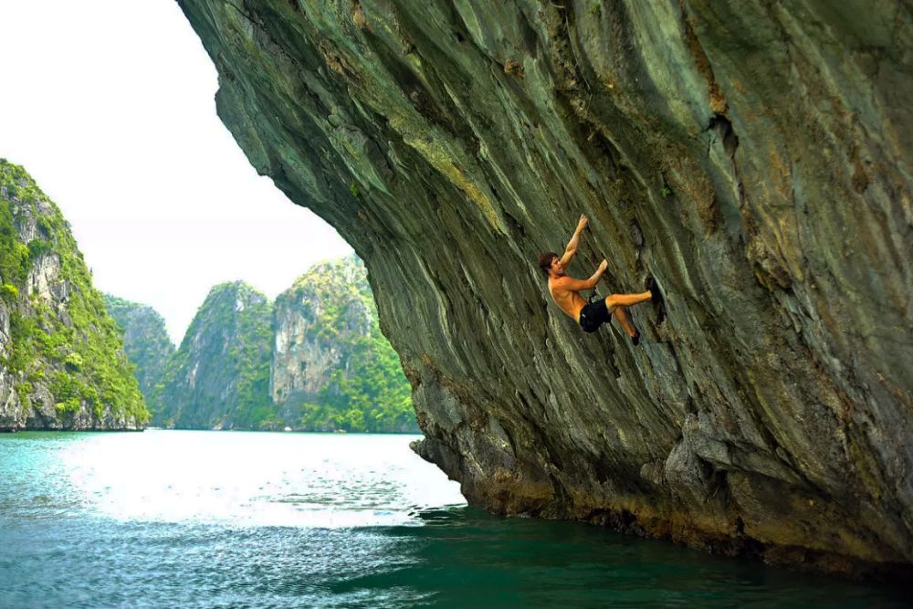 Un turista maschio sta facendo arrampicata su roccia nella baia di Ha Long
