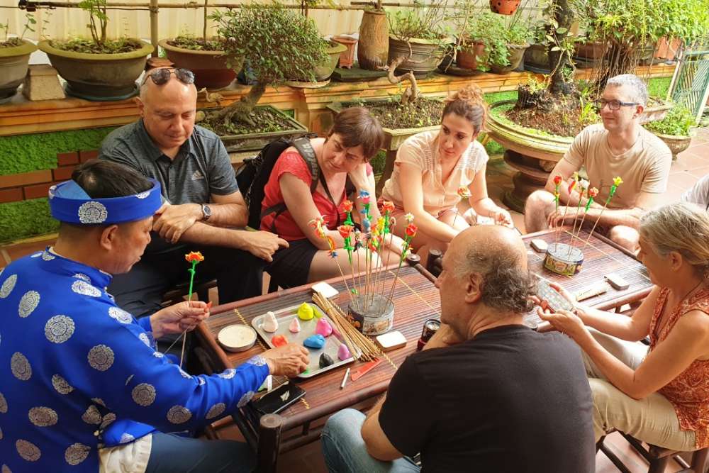 Un gruppo di clienti di Asiatica Travel sta osservando un artigiano creare i 'tò he'