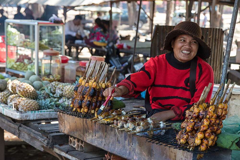 Una donna cambogiana vende cibo in una bancarella del mercato.